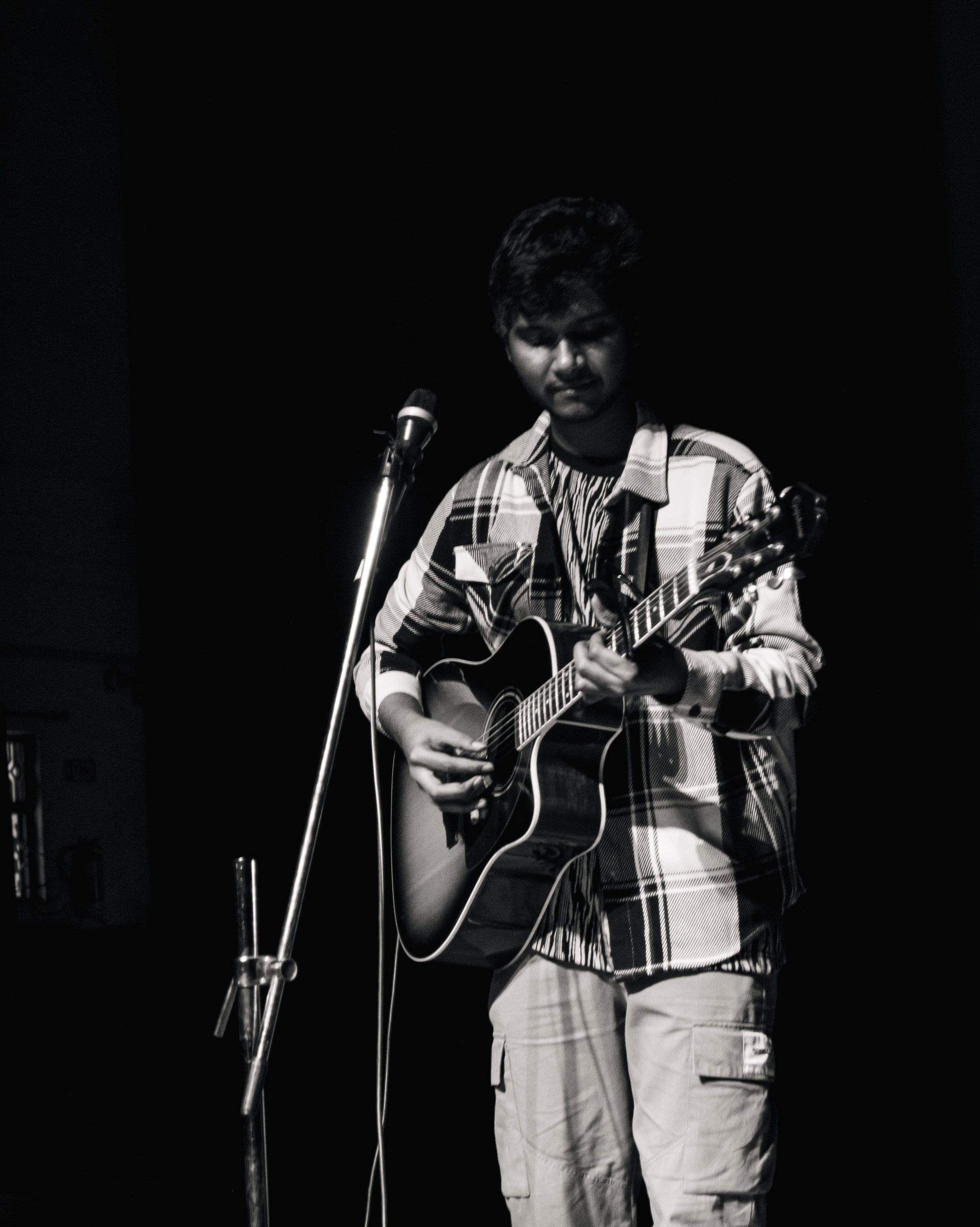 Black and white portrait of a guitarist singing at a microphone