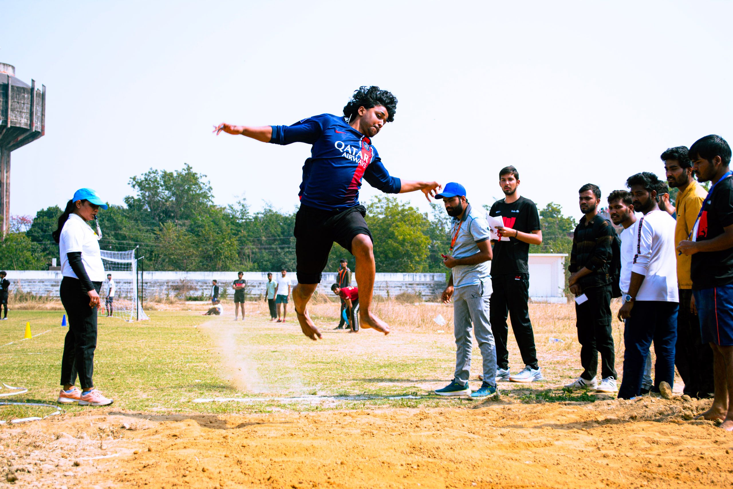 A player leaping high on an open ground as teammates watch