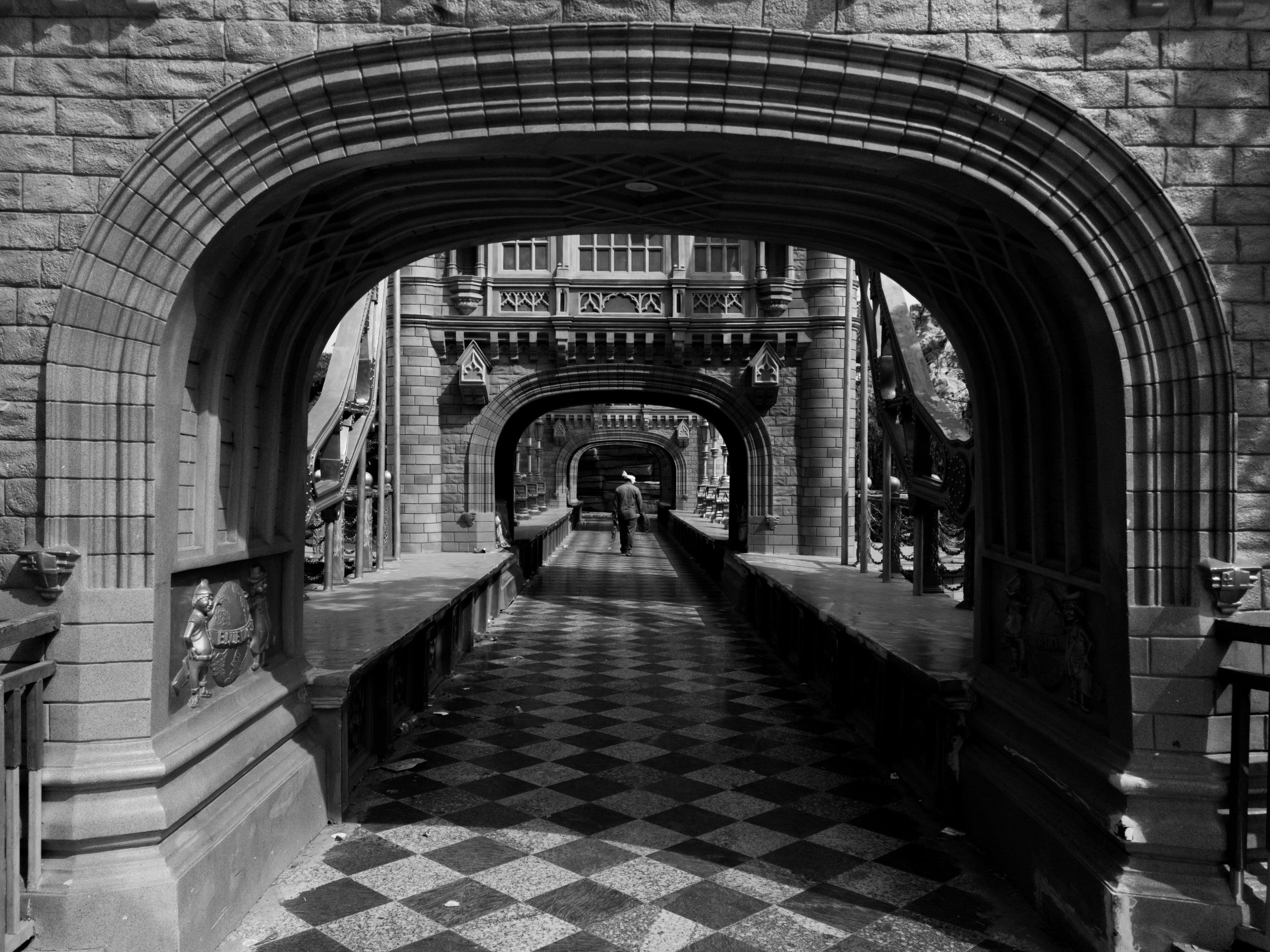 Black and white corridor of stone arches over a chequered floor