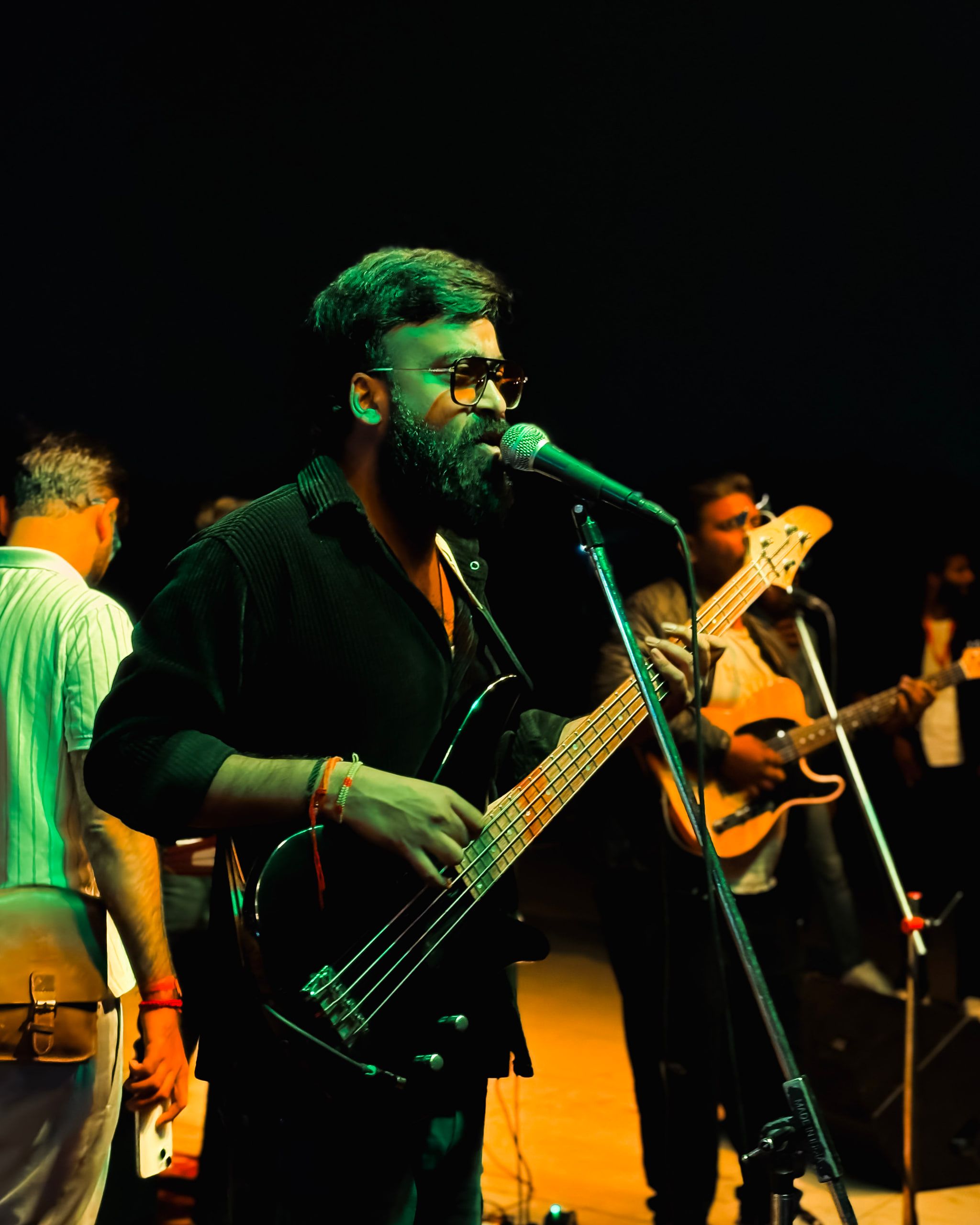 A bass player singing into a microphone on a night stage