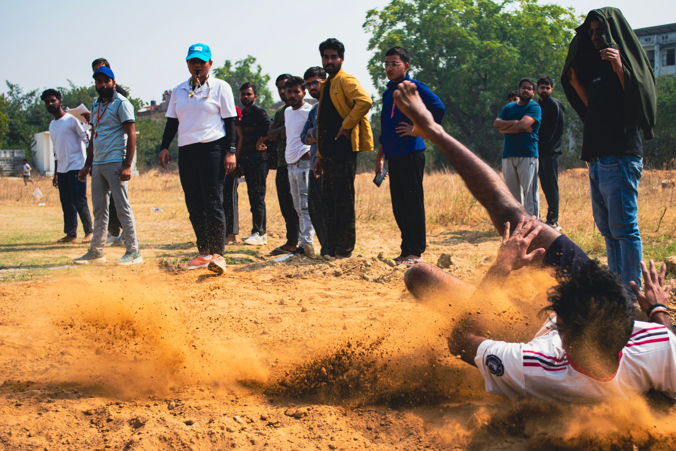 A player diving across dusty ground as spectators watch