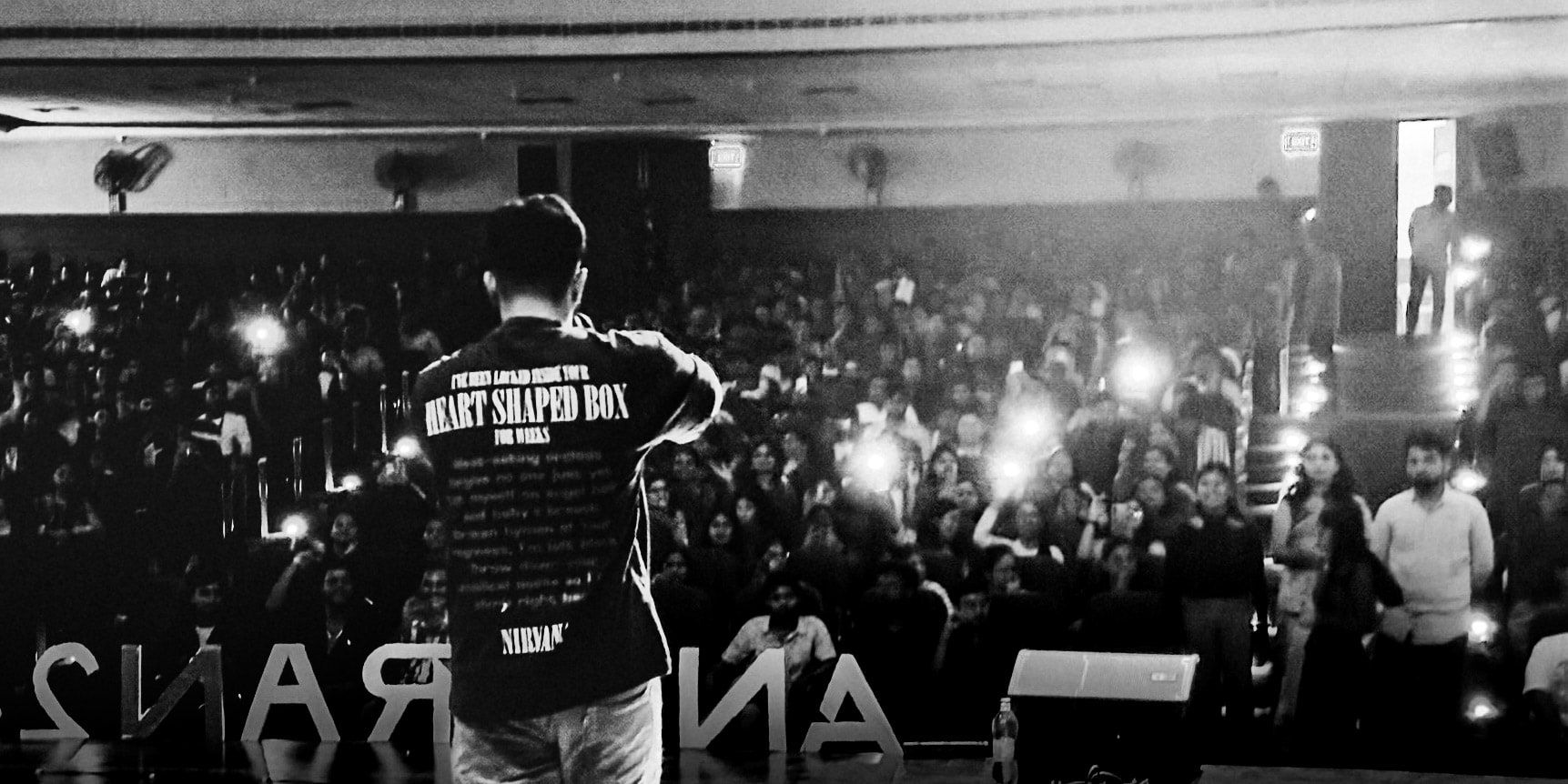 Wide black and white view of a performer and a packed hall