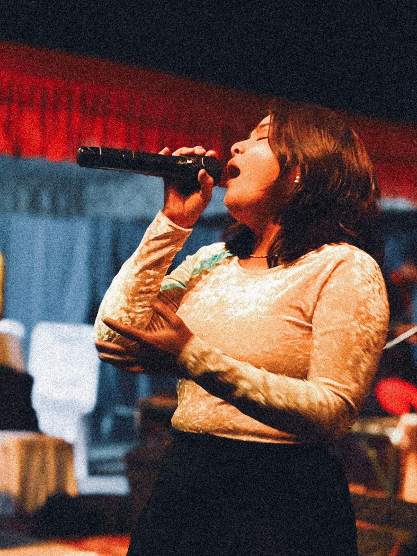 A woman singing into a microphone on a colourful stage