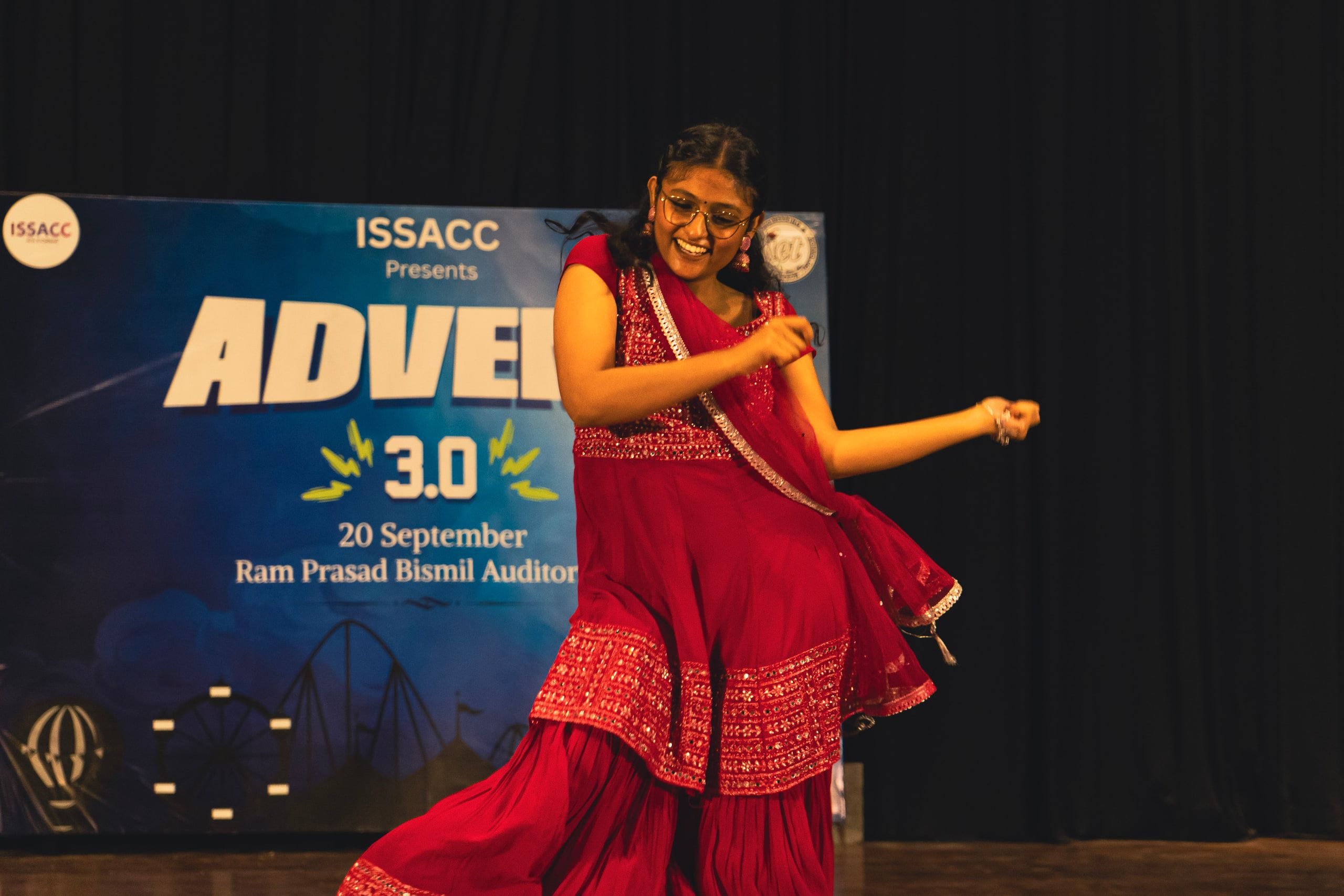 A dancer in a red lehenga mid-move on stage