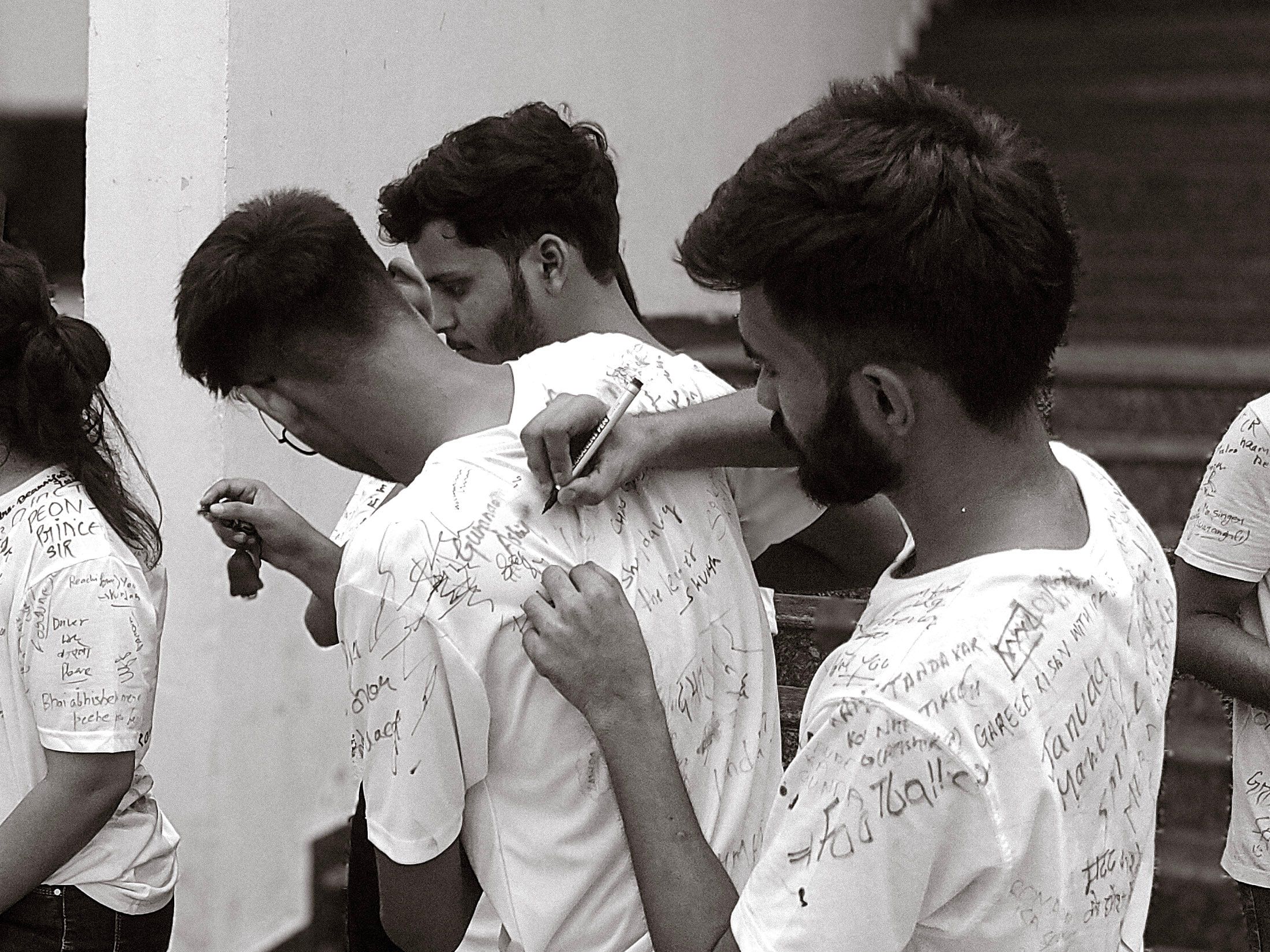 Students signing each other's shirts on the last day of college