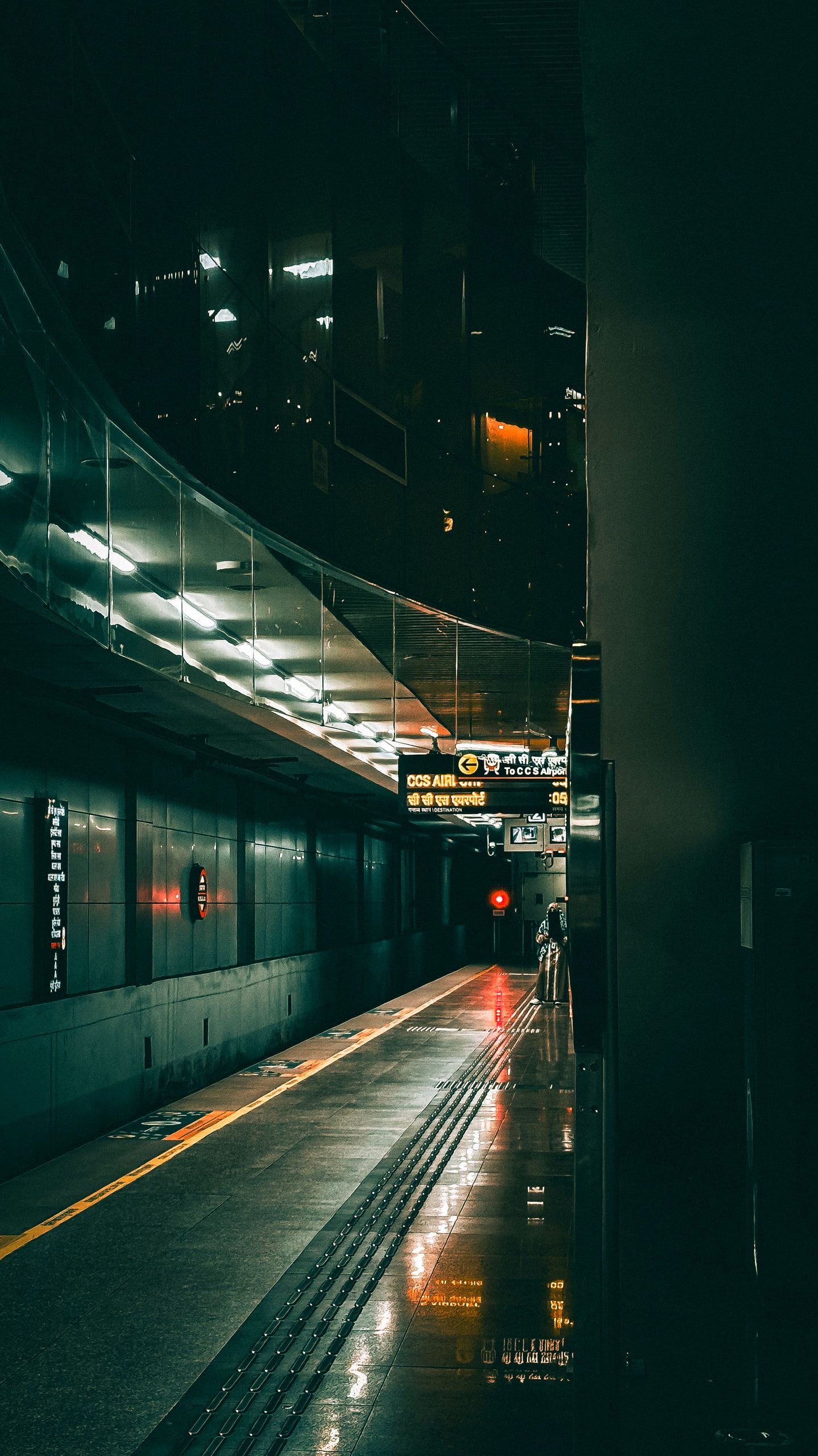 A metro train at a quiet platform at night under green light