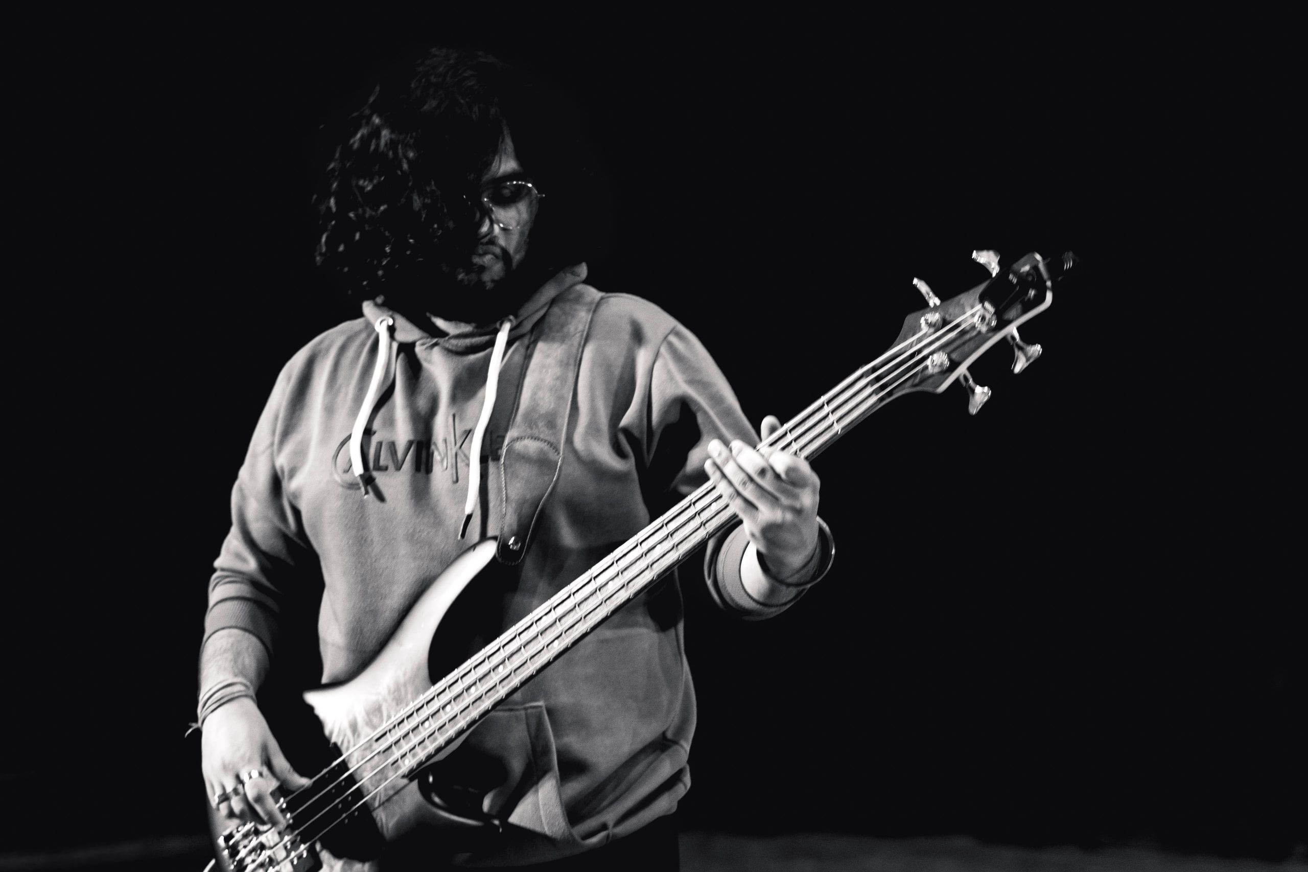 Black and white shot of a bassist playing on a dark stage