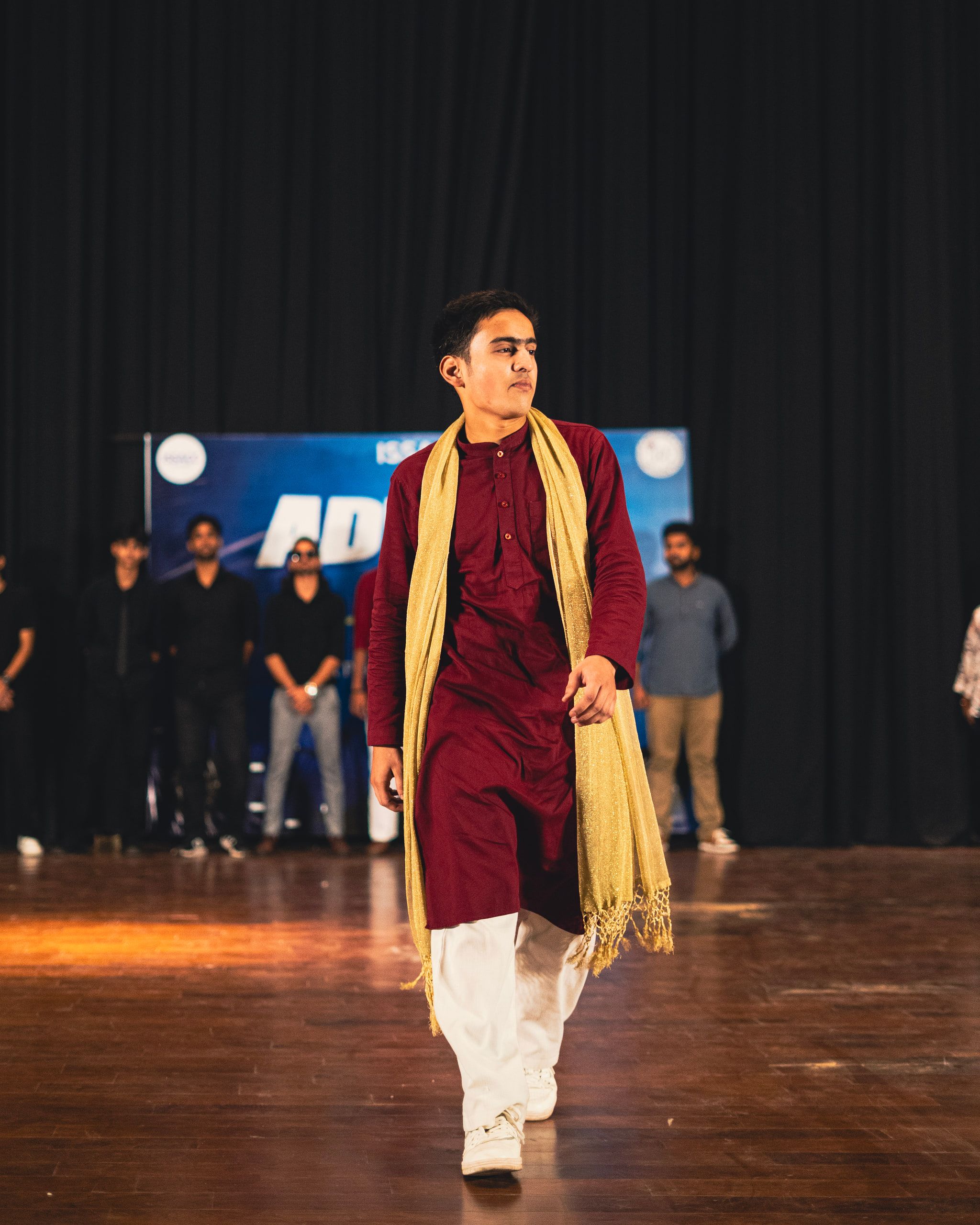 A man in a maroon kurta walking the stage