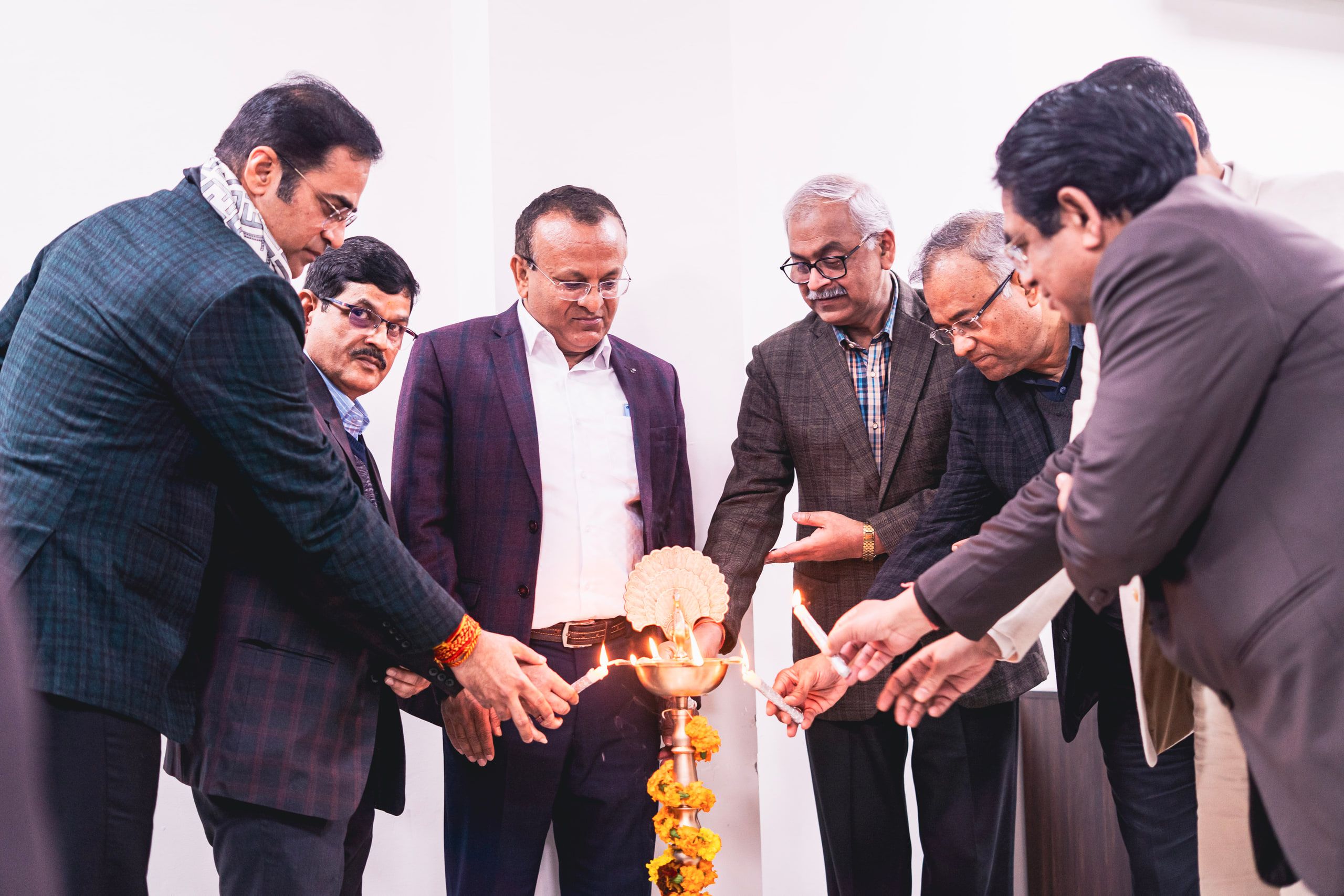 Officials in suits lighting a lamp at an opening ceremony