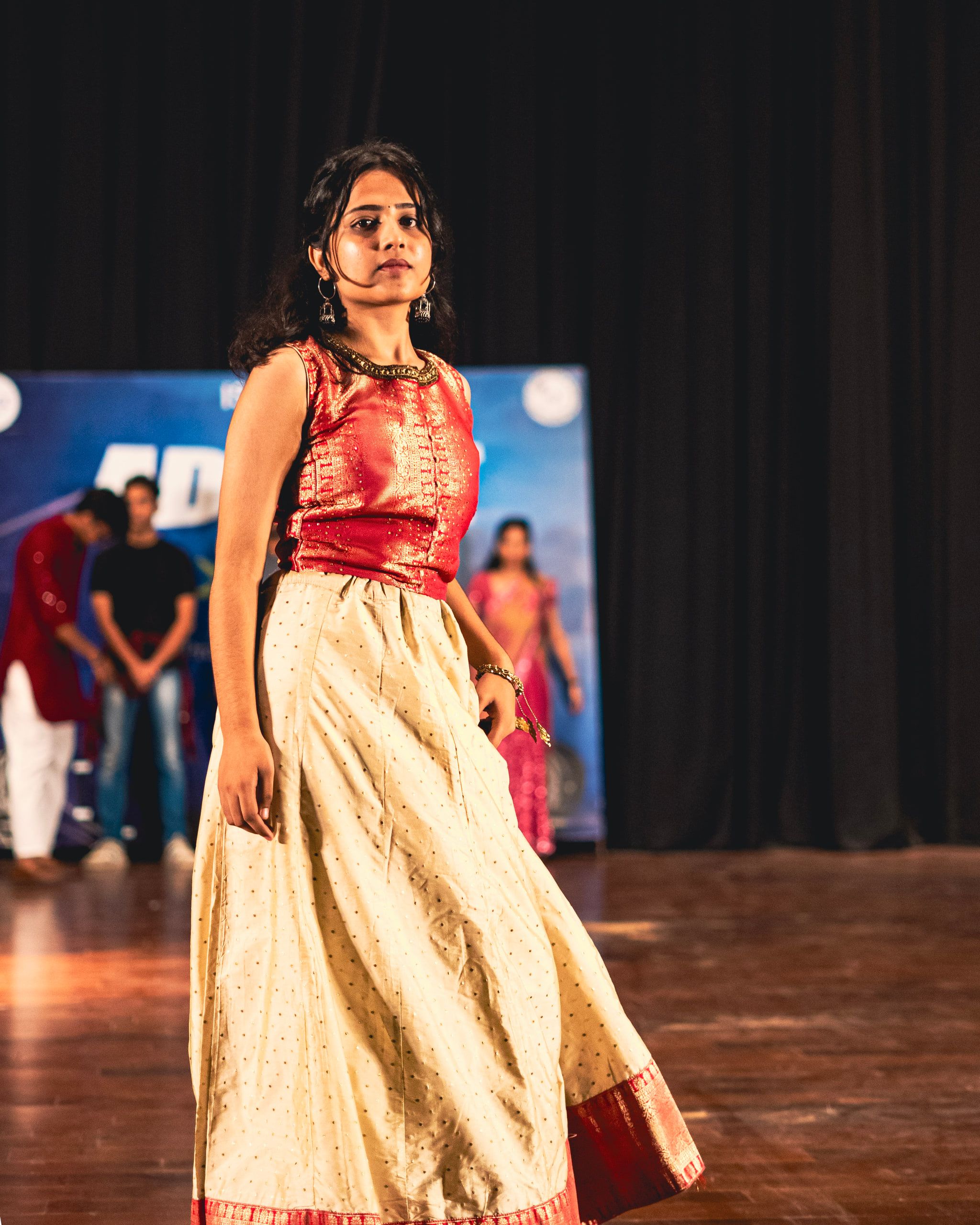 A woman in a red and cream lehenga walking the stage