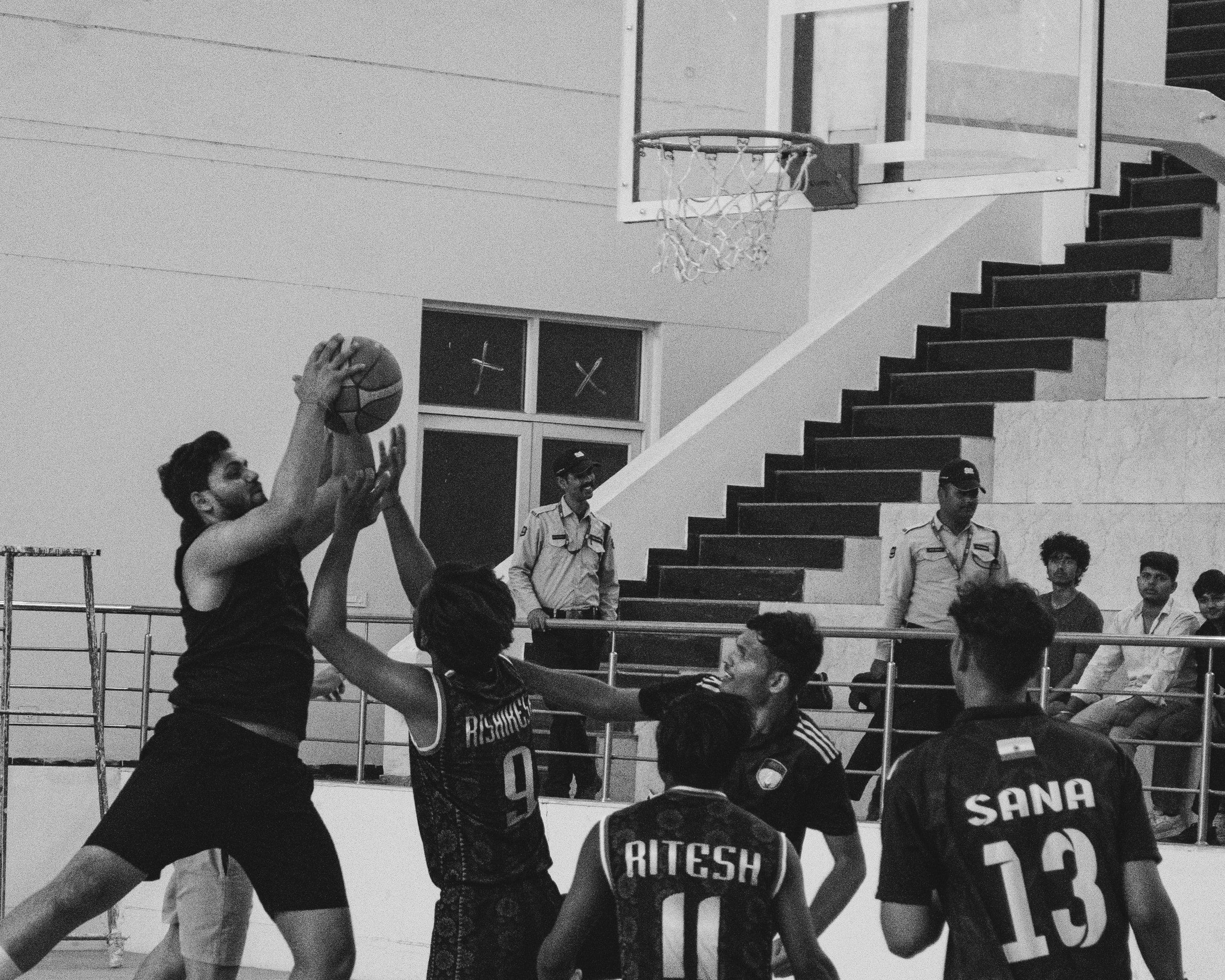 Black and white shot of basketball players leaping for a rebound