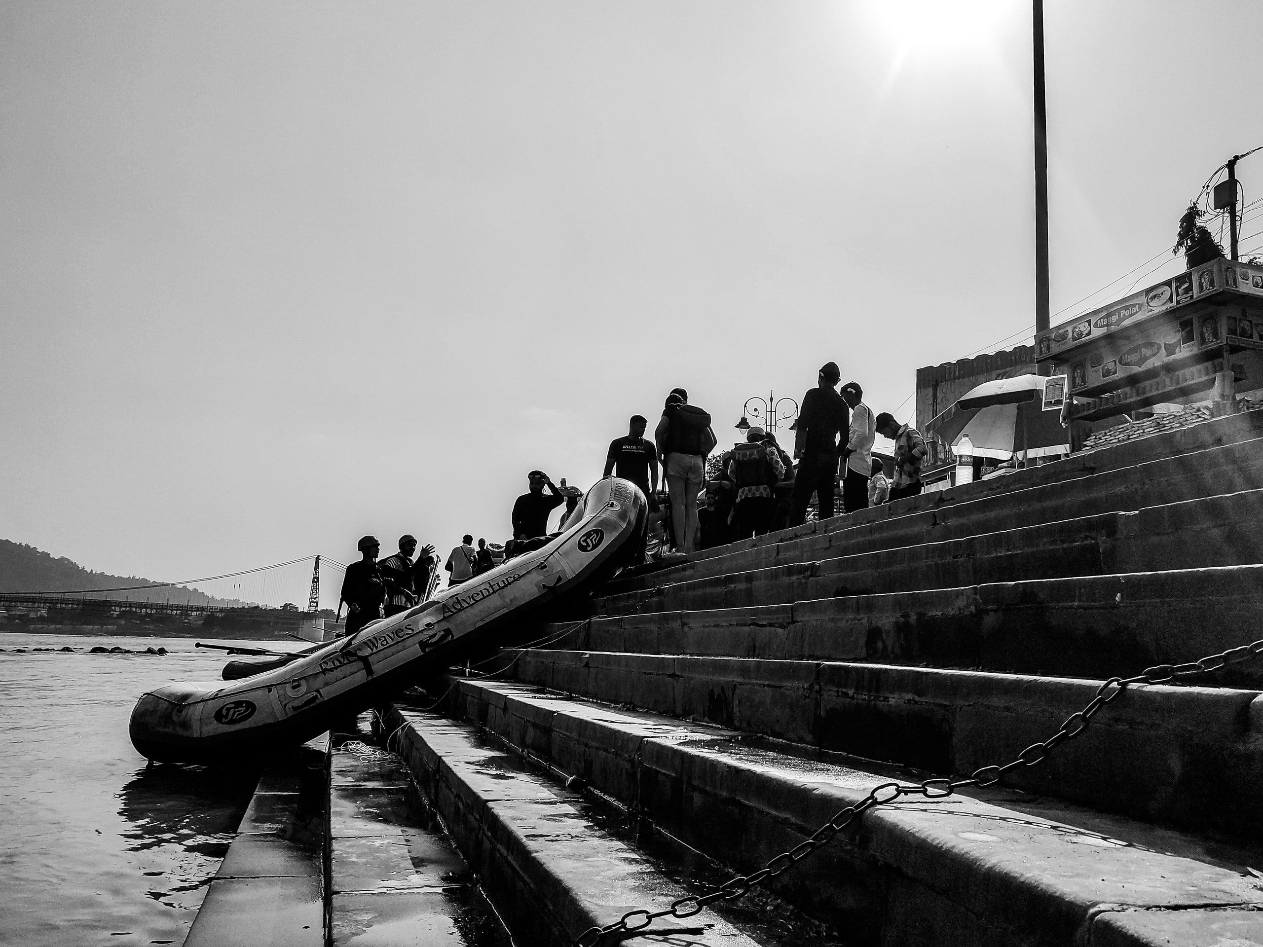 Black and white view of a boat and people on stone river steps