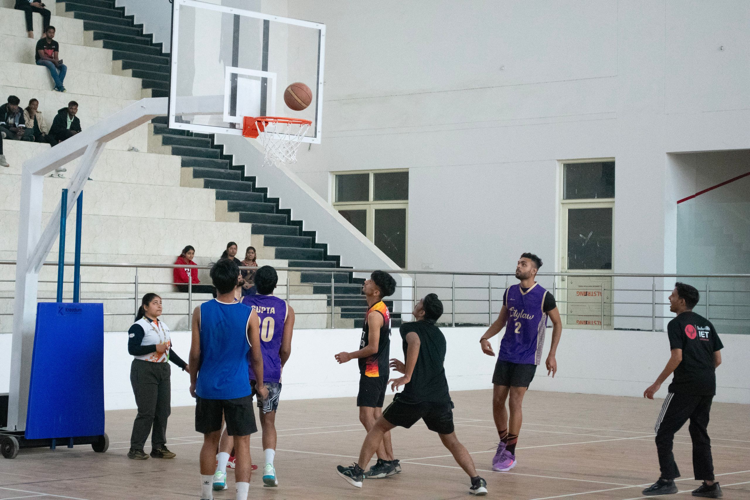 Basketball players chasing a loose ball under the hoop