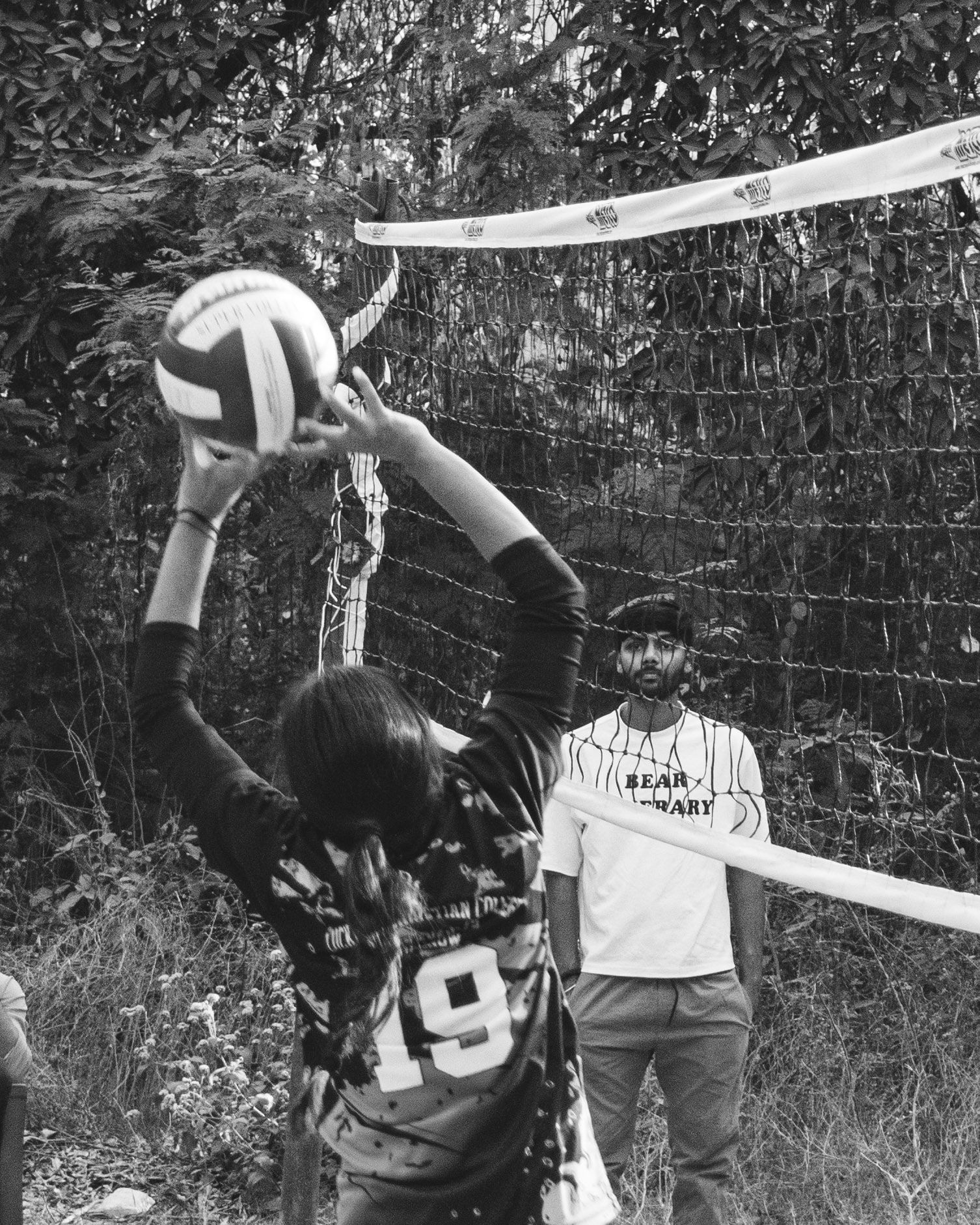 Black and white shot of a volleyball player setting the ball at the net