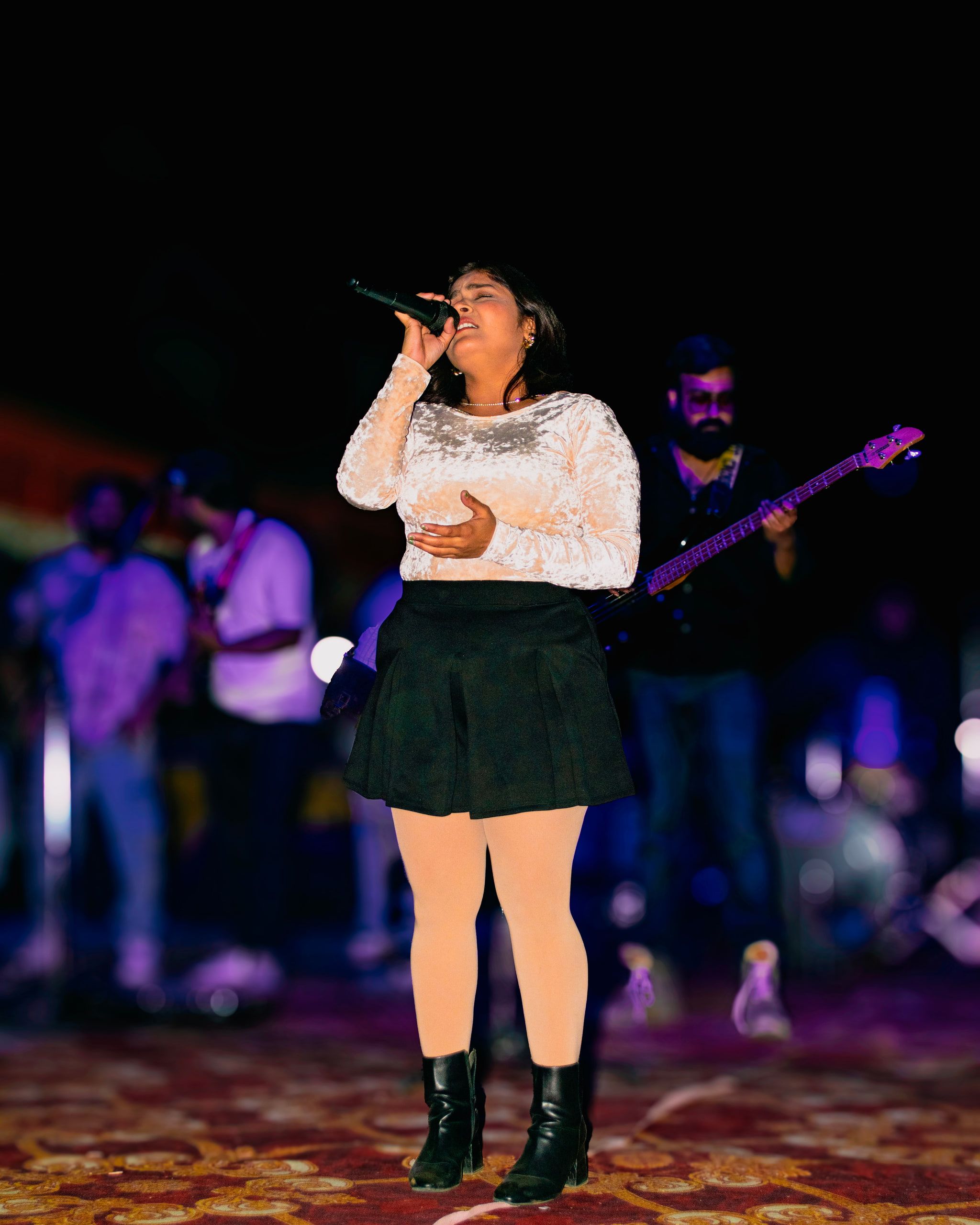 A singer in a white top performing on an outdoor stage