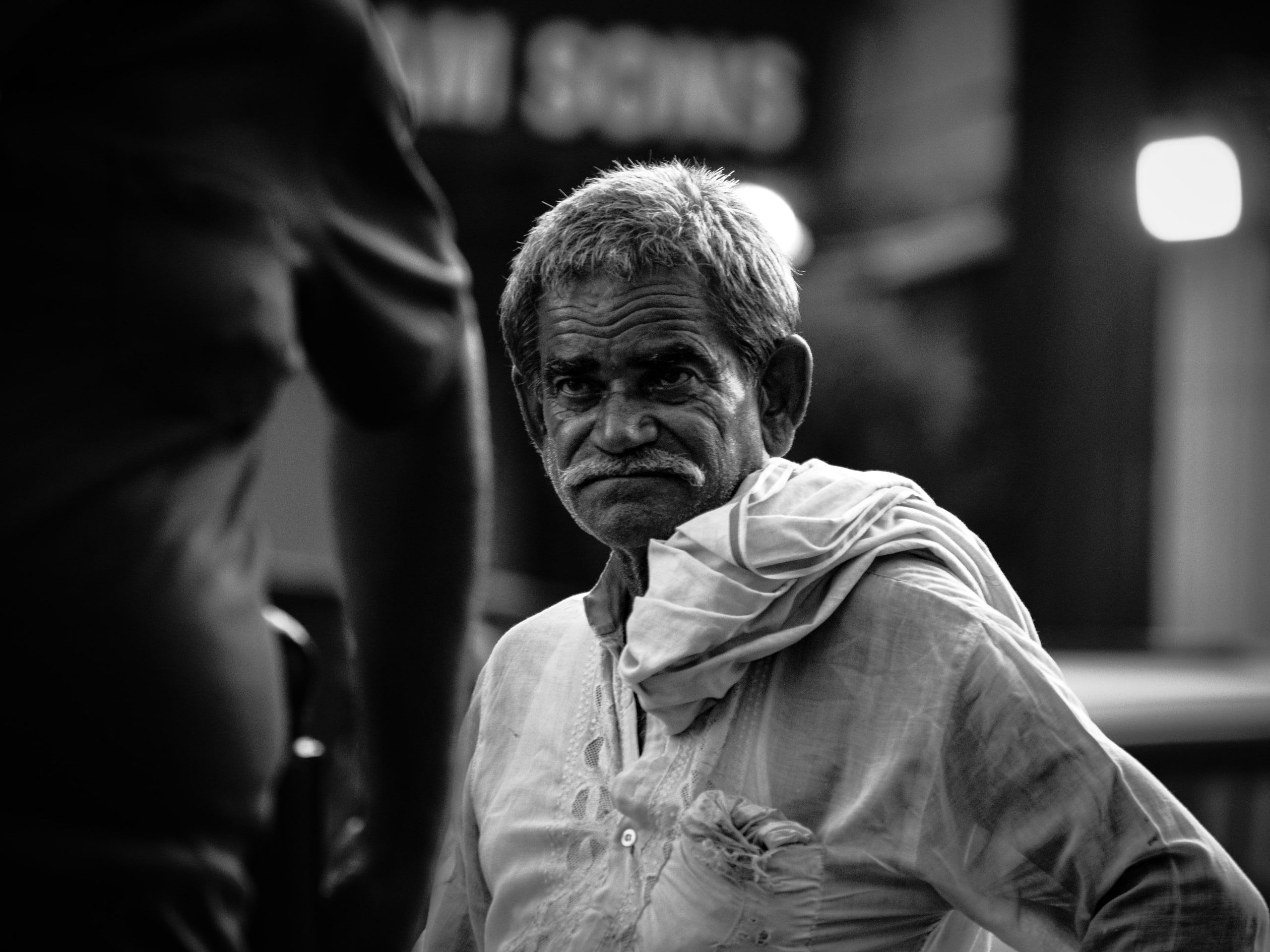 Black and white street portrait of an elderly man in a market