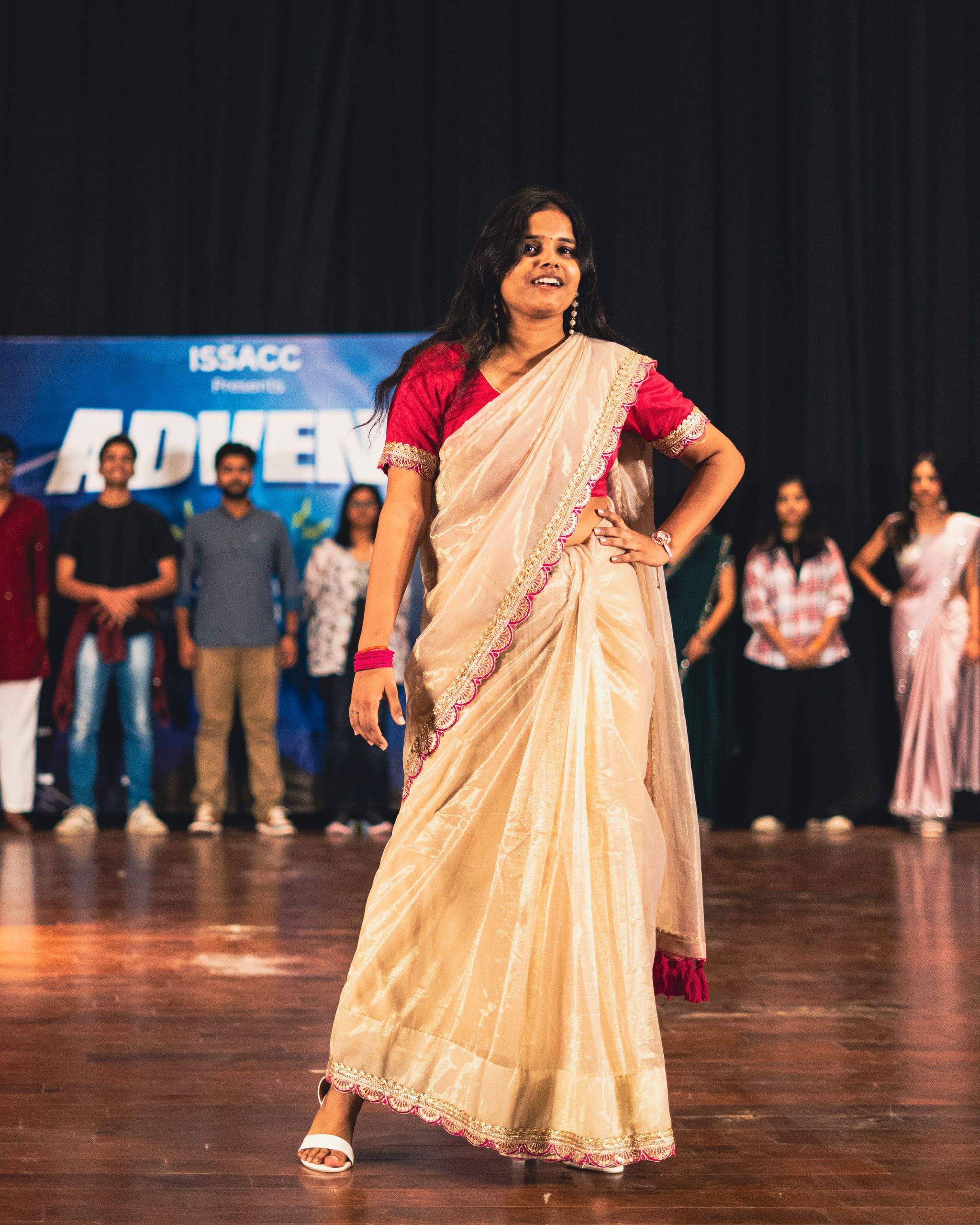 A woman in a cream saree posing on stage