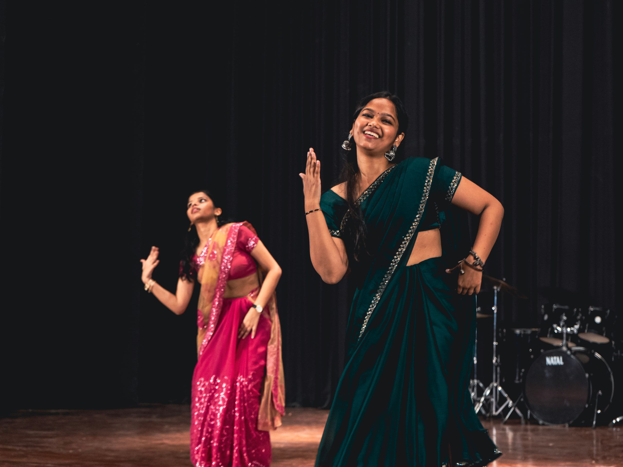 Two dancers in sarees performing on stage