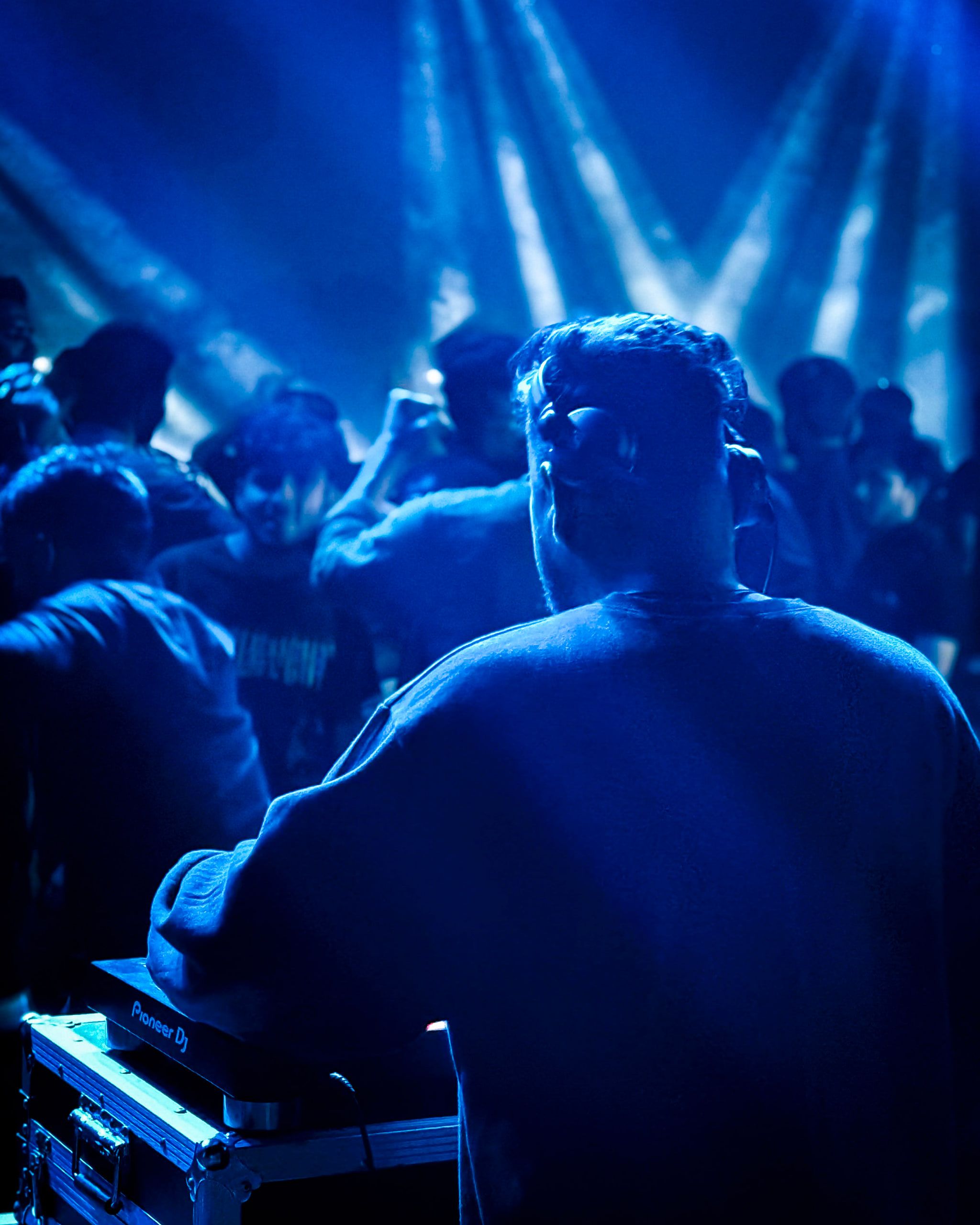 A man in a crowd bathed in blue stage beams