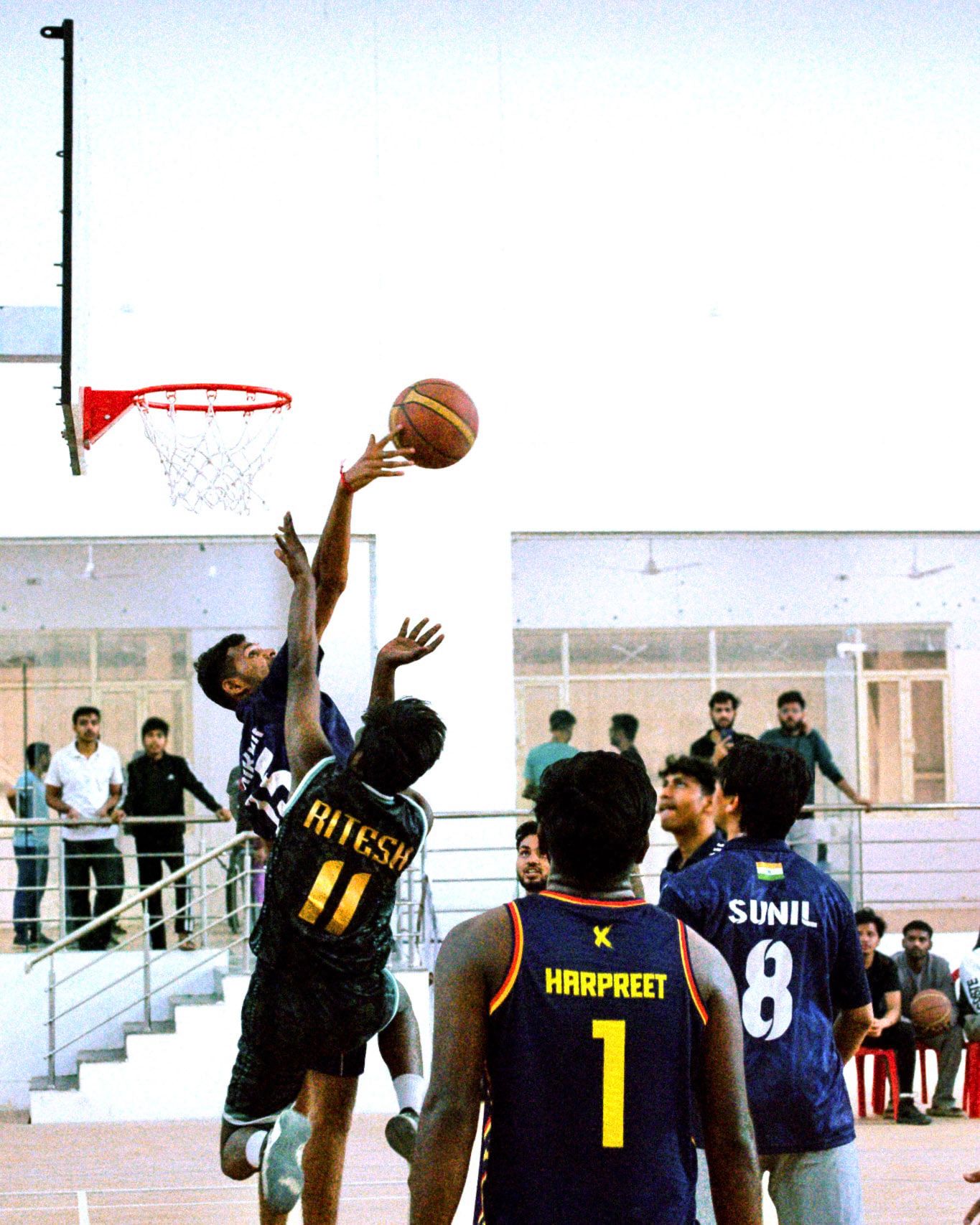 A basketball player reaching for the hoop over defenders